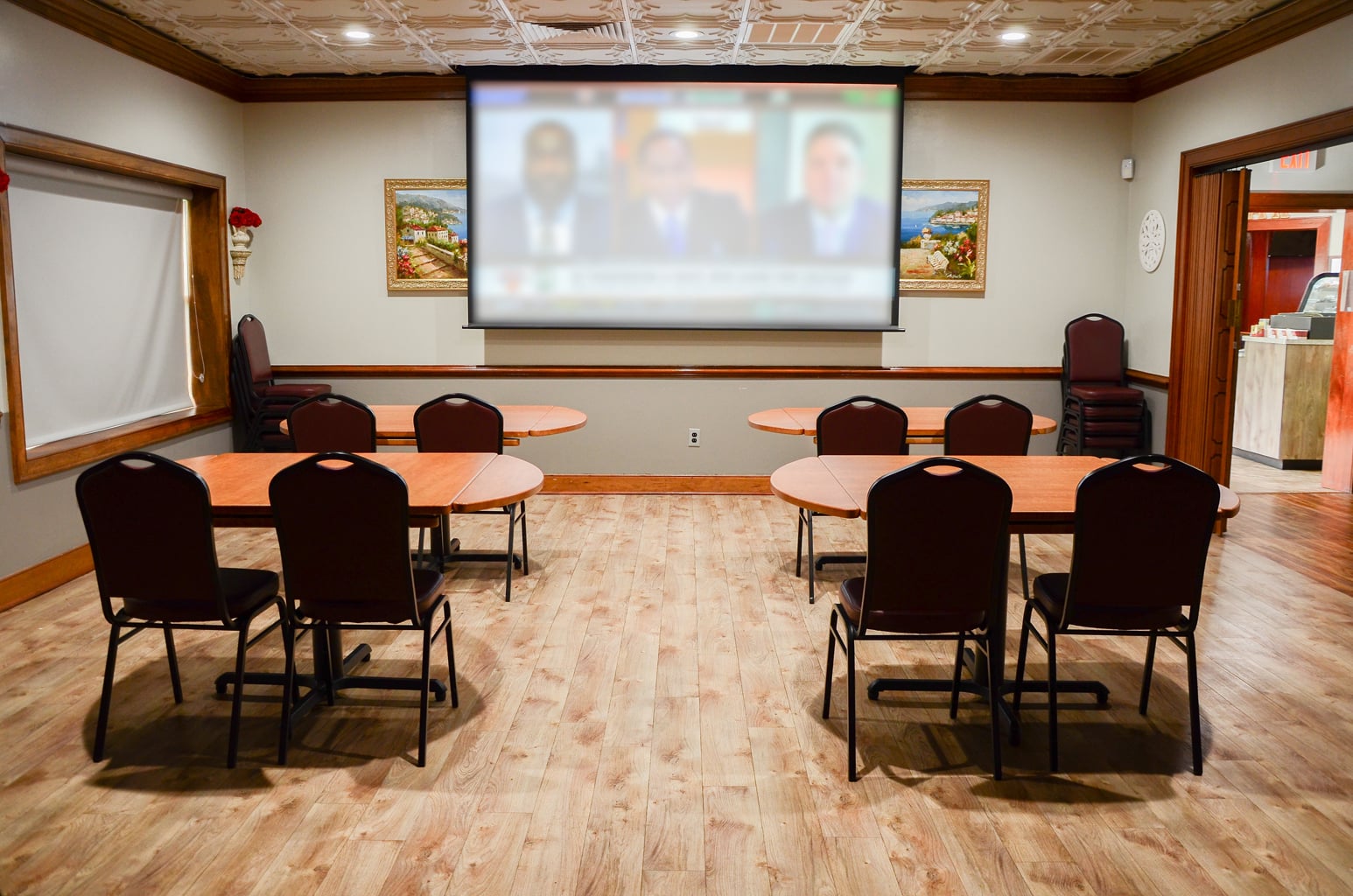 Private Room 1 at Ledo Pizza Lynchburg with tables, chairs, and a large projection screen
