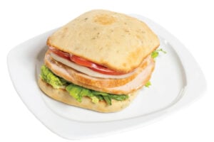 Turkey Focaccia Sandwich with thick-cut turkey slices, on a focaccia roll with lettuce, tomatoes, mayo, and smoked provolone cheese.