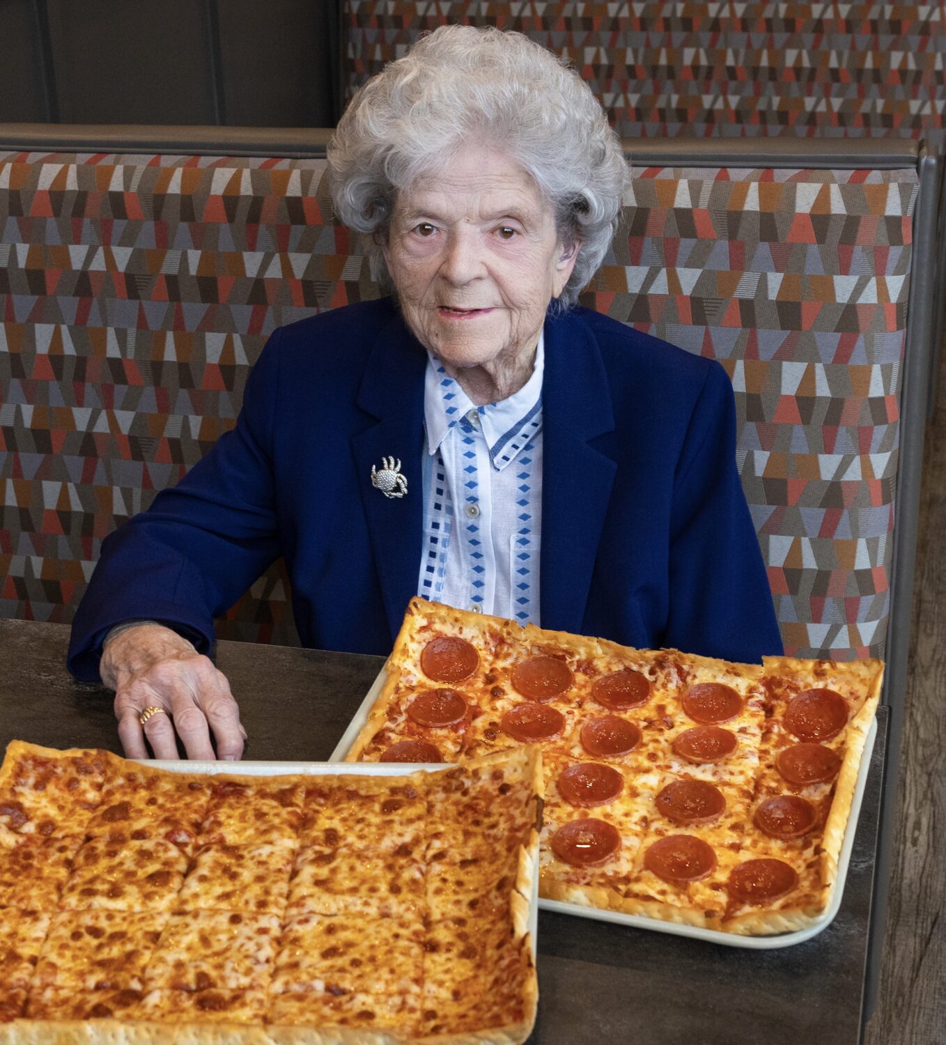 Grandma Beall with a cheese pizza and a pepperoni pizza.