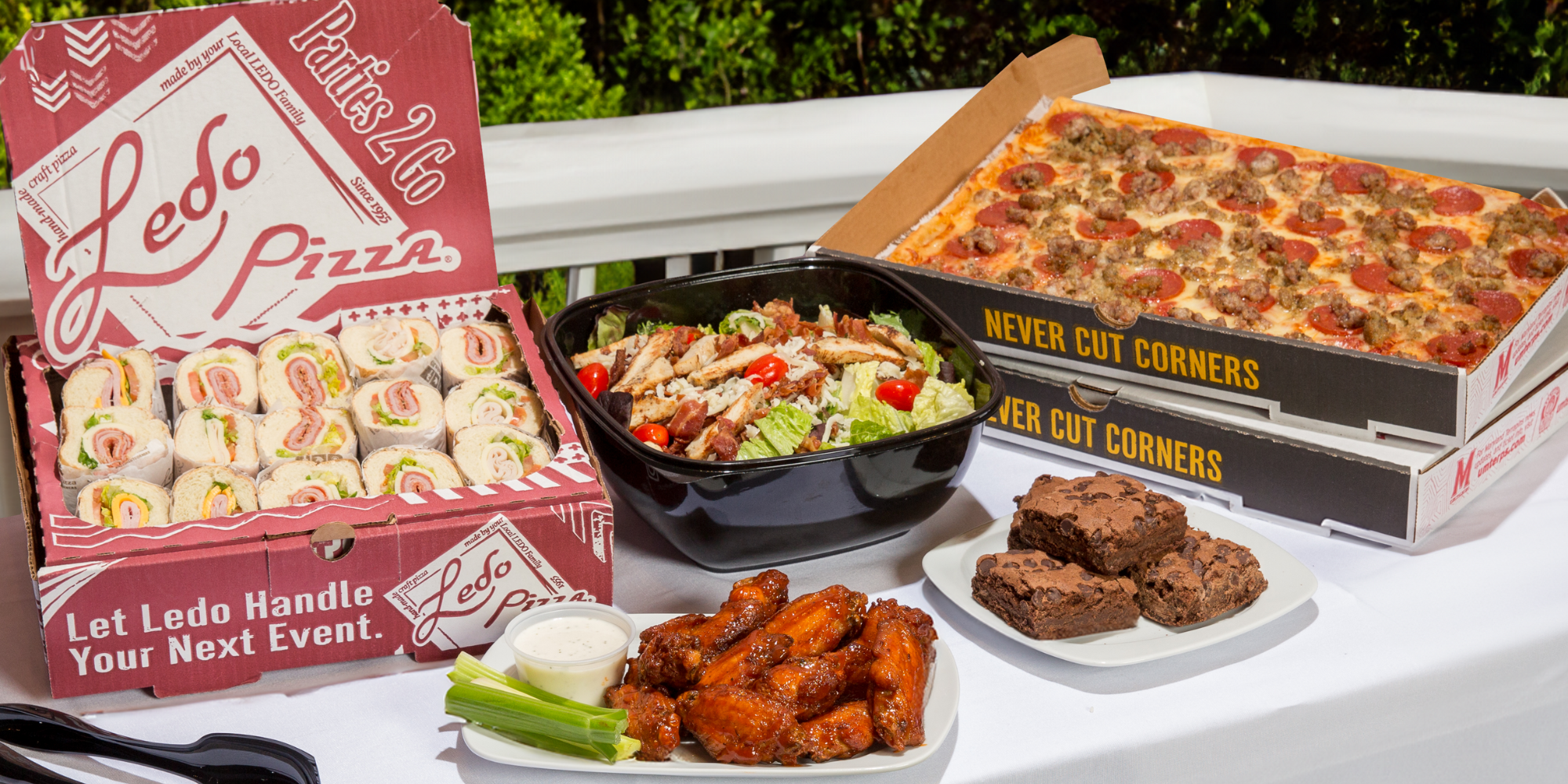 Ledo Pizza catering spread with pizza, subs, salad, wings and brownies